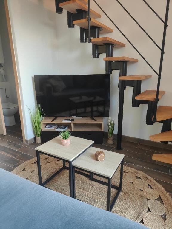 Jungle Loft, séjour avec escalier hélicoïdal en bois et grand téléviseur, meublé de tourisme à Tillé, aéroport de Beauvais