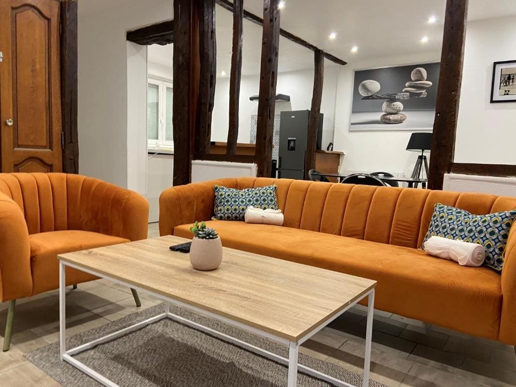 La Galerie, séjour avec canapés orange et colombages apparents, meublé de tourisme à Tillé, aéroport de Beauvais